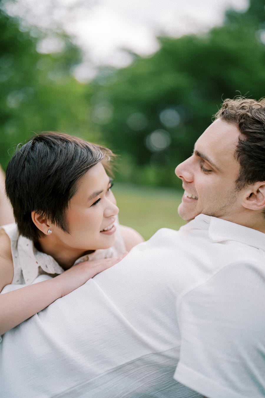 Smiling couple enjoying a tender moment outdoors against a blurred green background