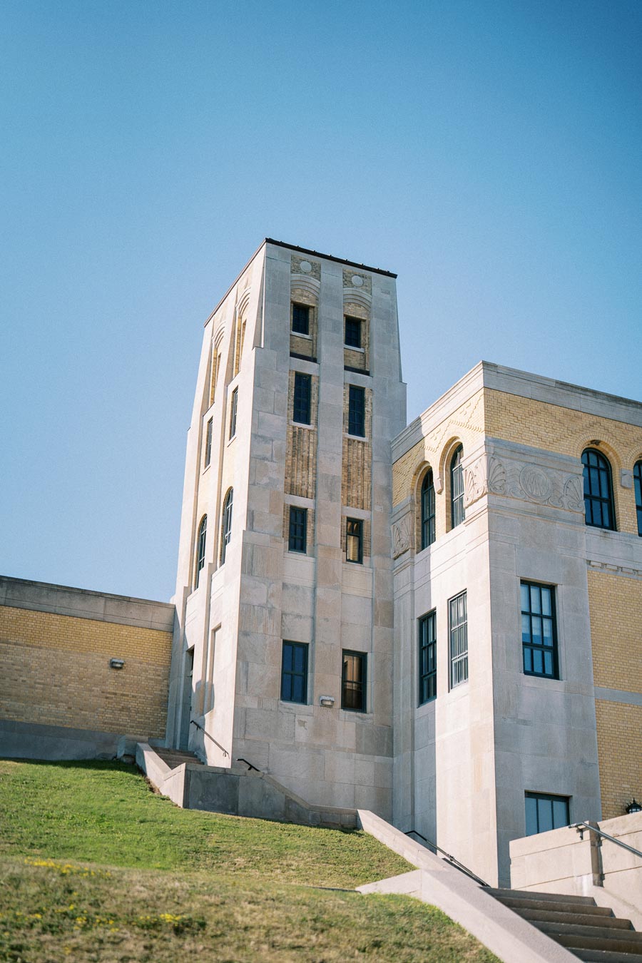 Historic stone building with a tall tower and arched windows under a clear blue sky