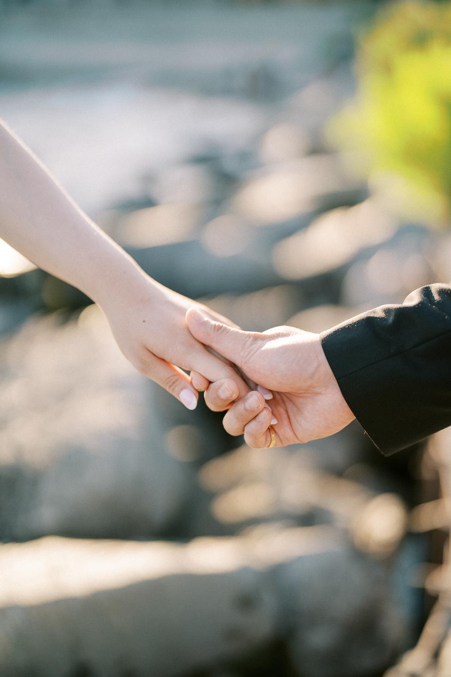 Close-up of a couple holding hands, symbolizing love and connection, with a soft-focus background.