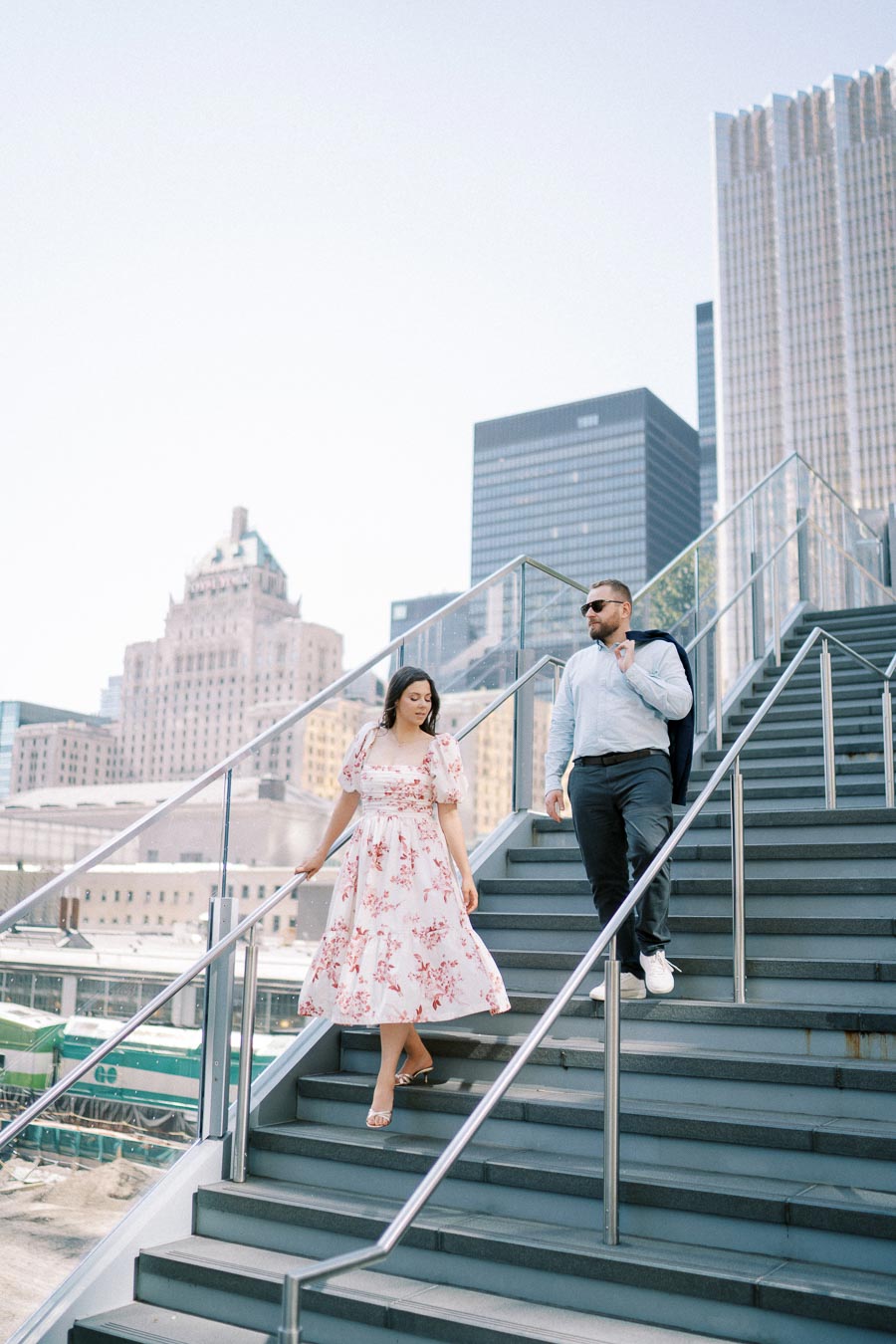 Stylish couple walking down urban staircase with modern cityscape in background