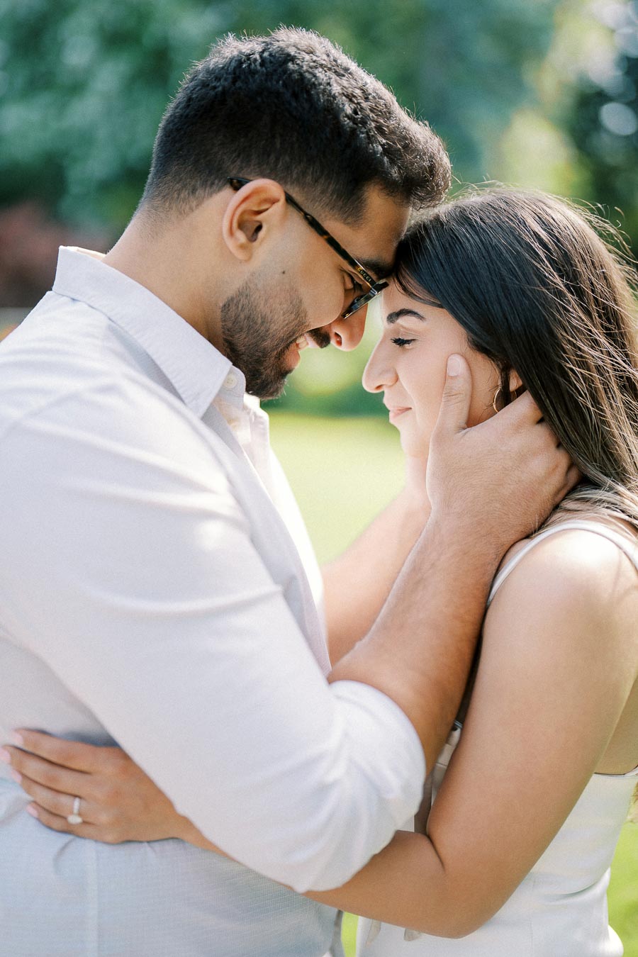 A couple embraces tenderly in a sunlit garden, showcasing love and intimacy.