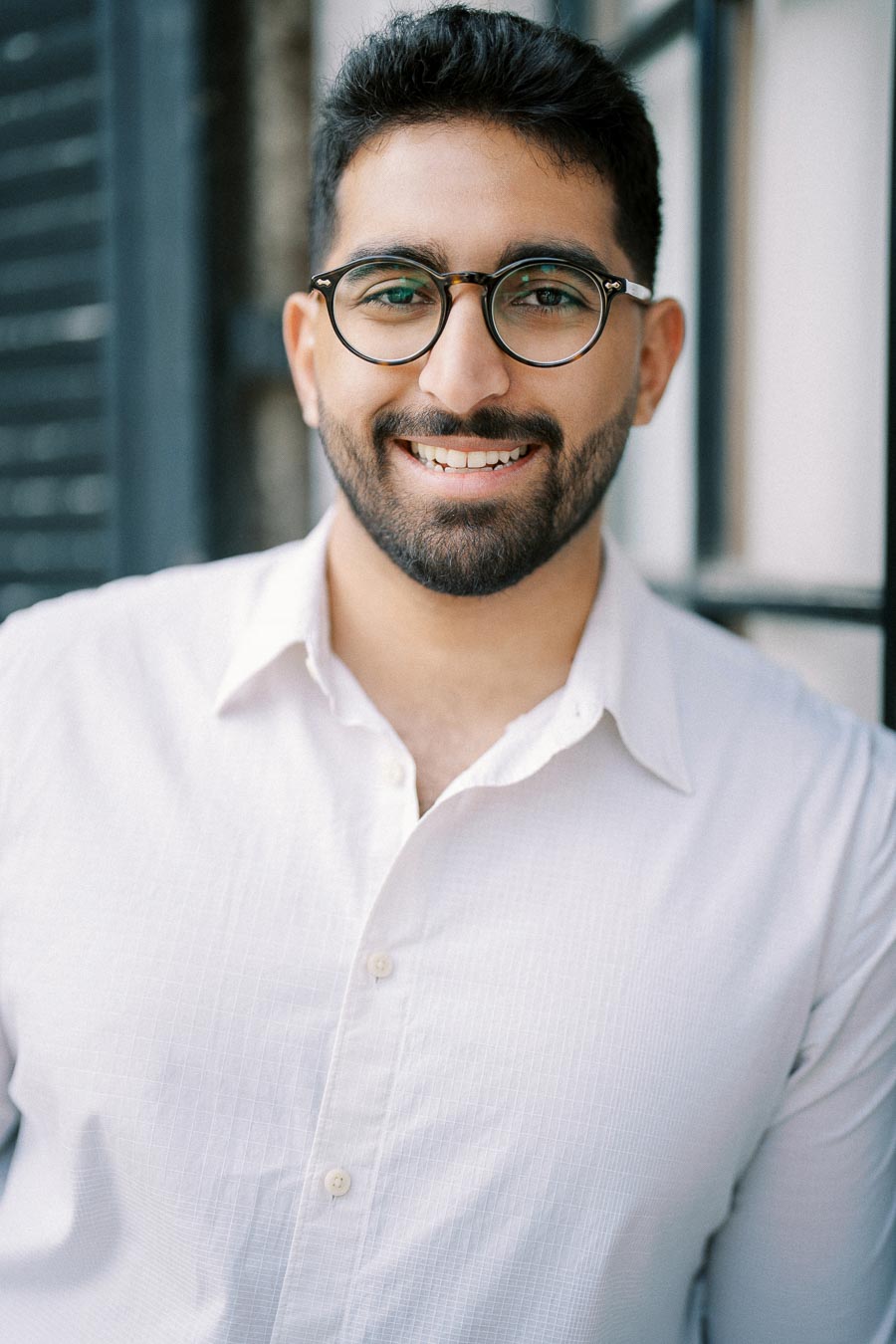 Smiling man with glasses and beard wearing a white shirt