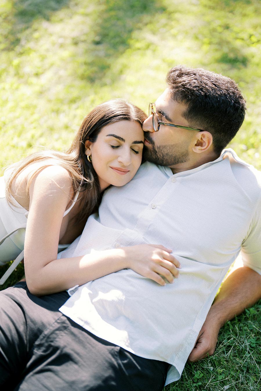 A couple relaxing on the grass, embracing and enjoying a sunny day in the park.