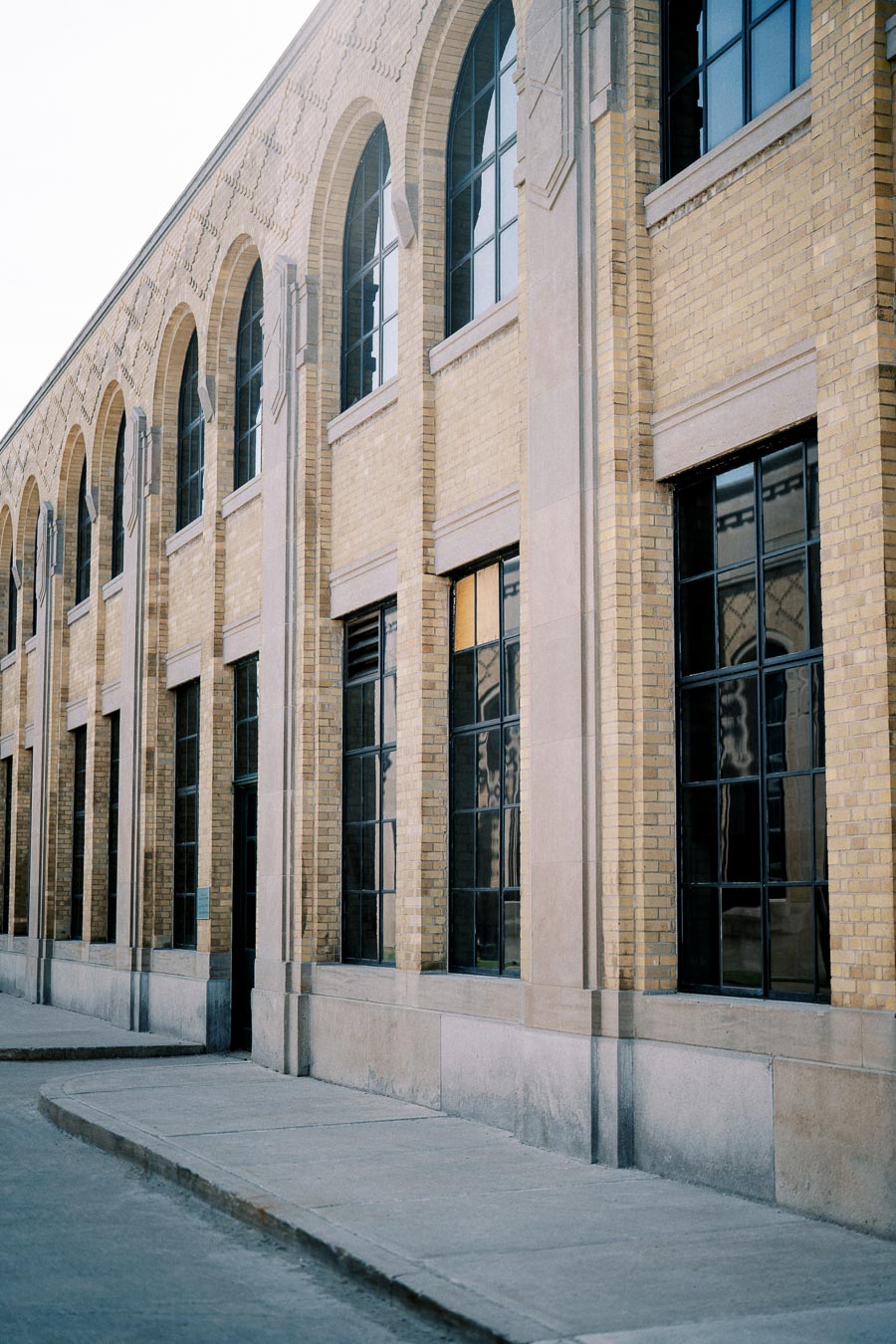 Exterior view of a classic brick building with tall arched windows, showcasing architectural details and symmetry.