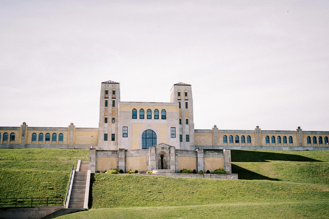Front view of a historic building in Denison, Texas, showcasing its prominent towers and large arched windows, set against a clear sky with a lush green lawn in the foreground.