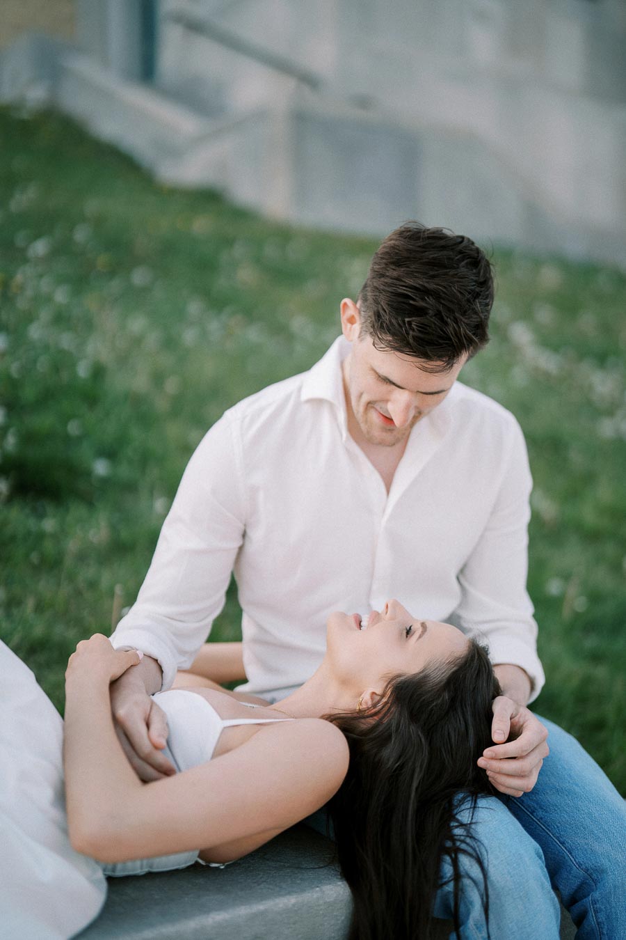 A couple enjoying a romantic moment in the park, smiling and embracing on a sunny day.