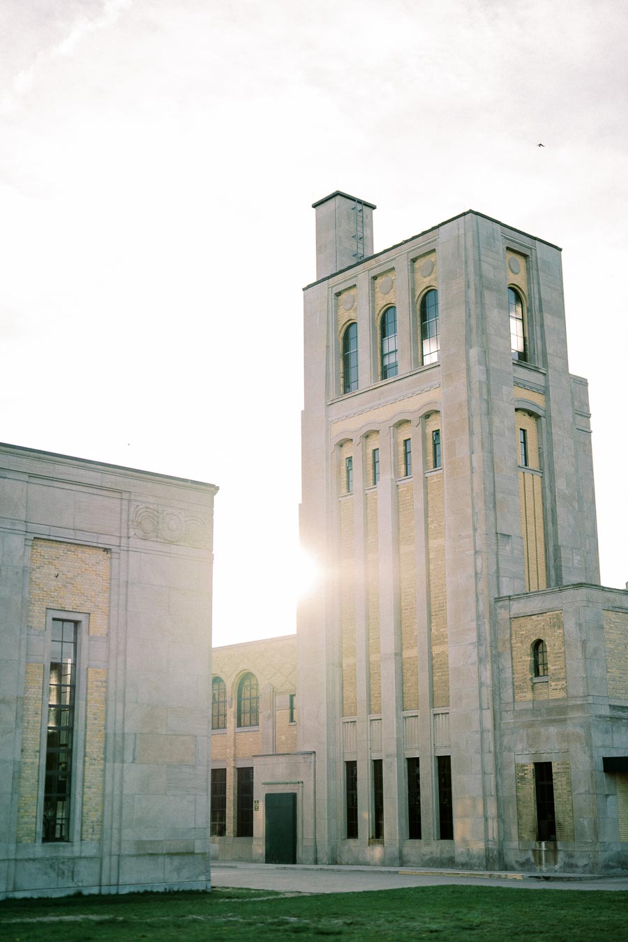 Tall historical stone building with arched windows, bathed in sunlight against a clear sky.