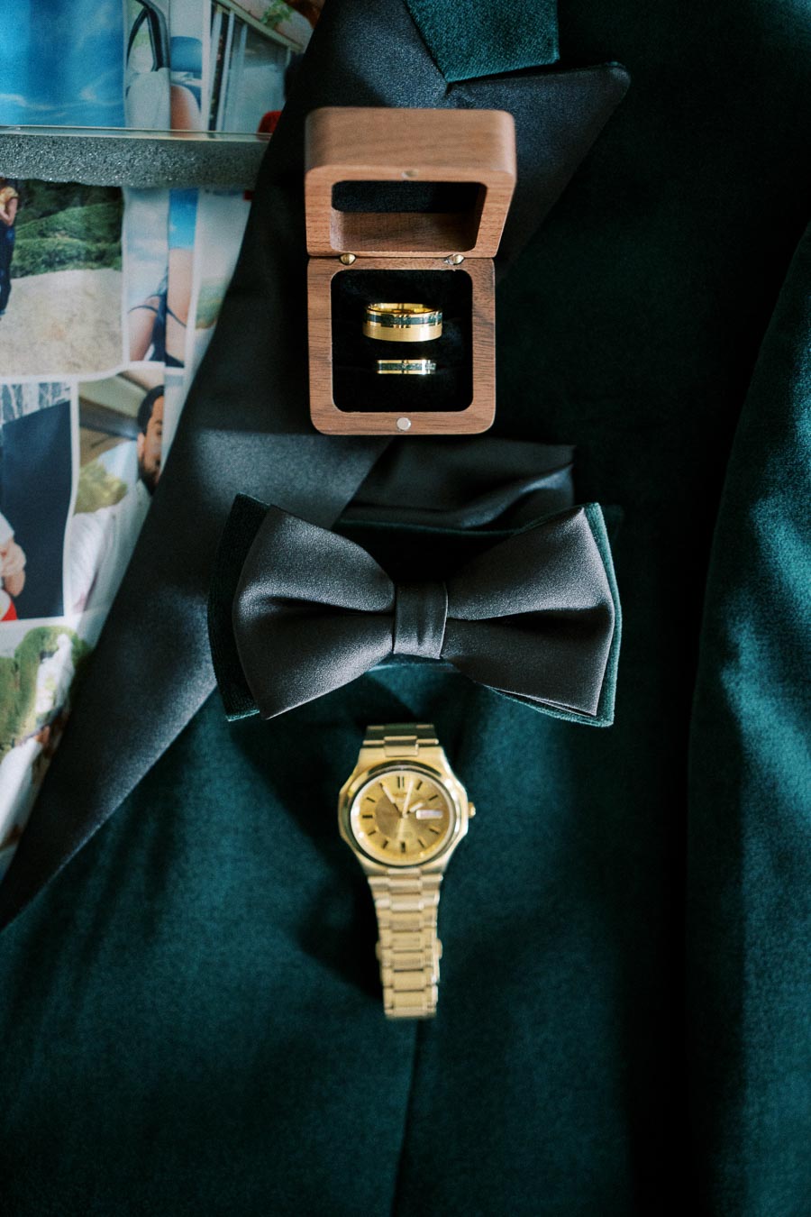 Tuxedo jacket with a black bow tie, wooden ring box, and gold wristwatch, highlighting elegant wedding accessories and style.