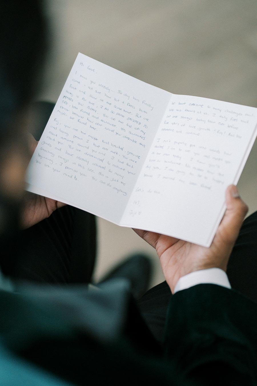 A person holding and reading a handwritten letter with heartfelt messages, conveying personal sentiments in a formal setting.