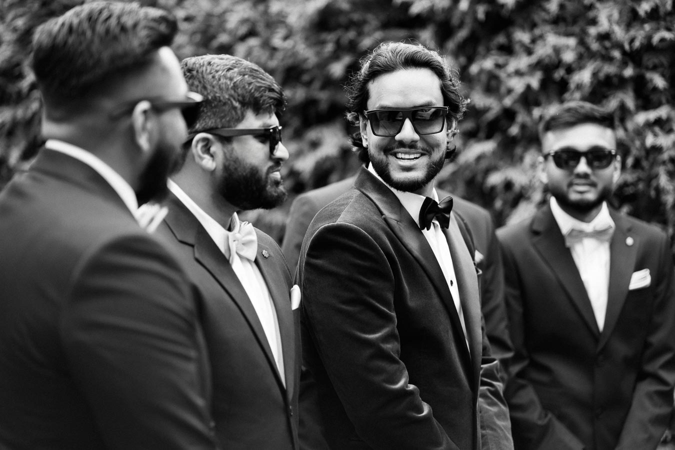 A group of men wearing sunglasses and formal suits, gathered outdoors, exuding a stylish and confident vibe.