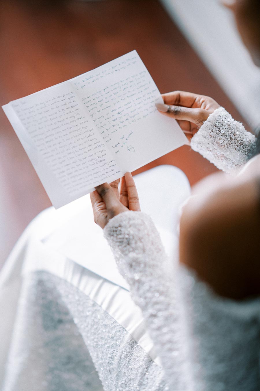 Bride reading a handwritten wedding letter, wearing a lace gown, capturing an intimate and emotional moment on her special day.