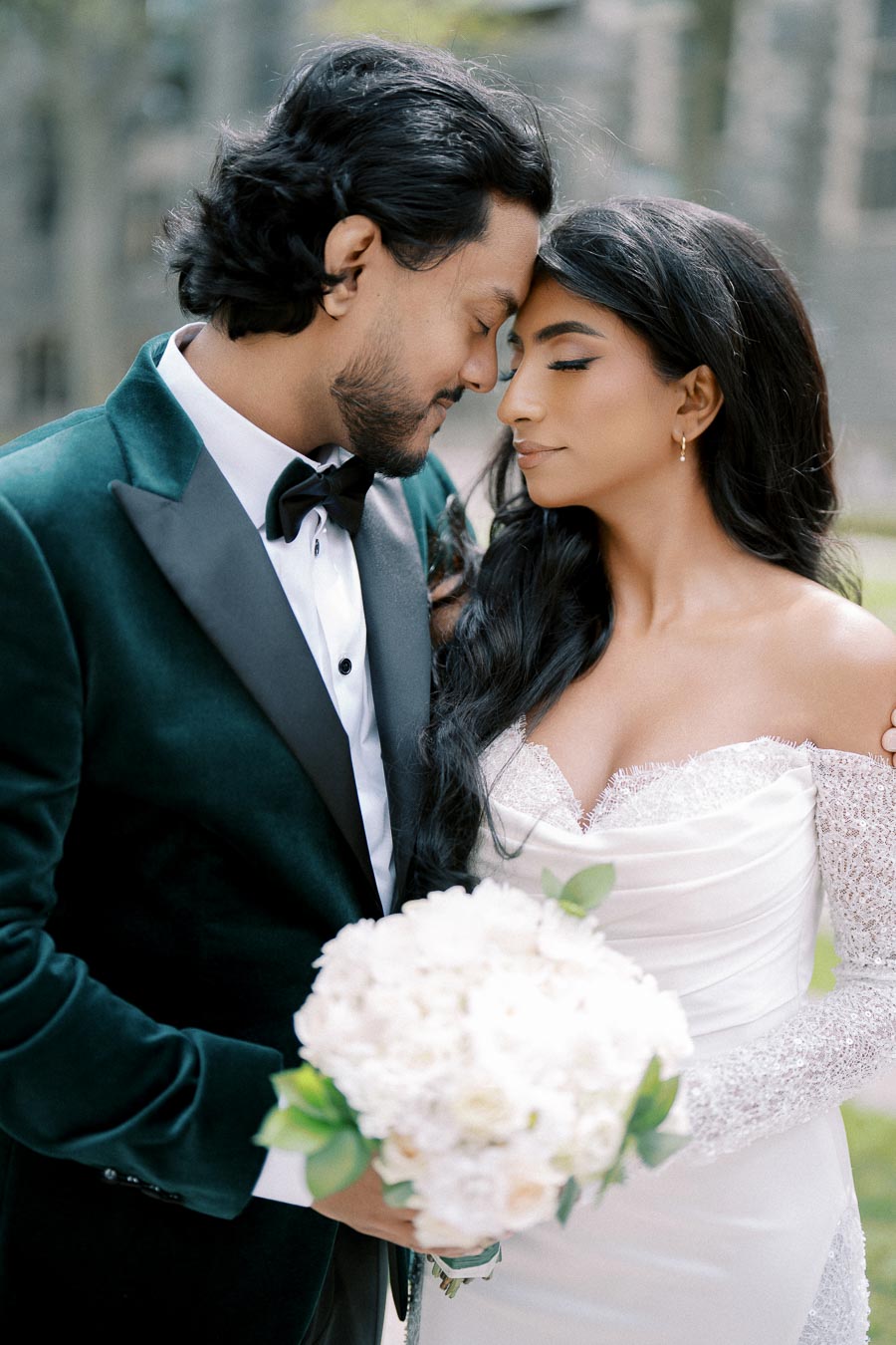 A bride and groom embrace tenderly on their wedding day, with the bride holding a bouquet of white flowers, capturing a moment of love and joy.