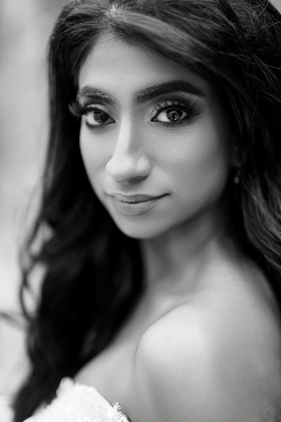 Black and white portrait of a woman with long hair and expressive eyes, showcasing elegant makeup and a soft expression, perfect for beauty and fashion themes.
