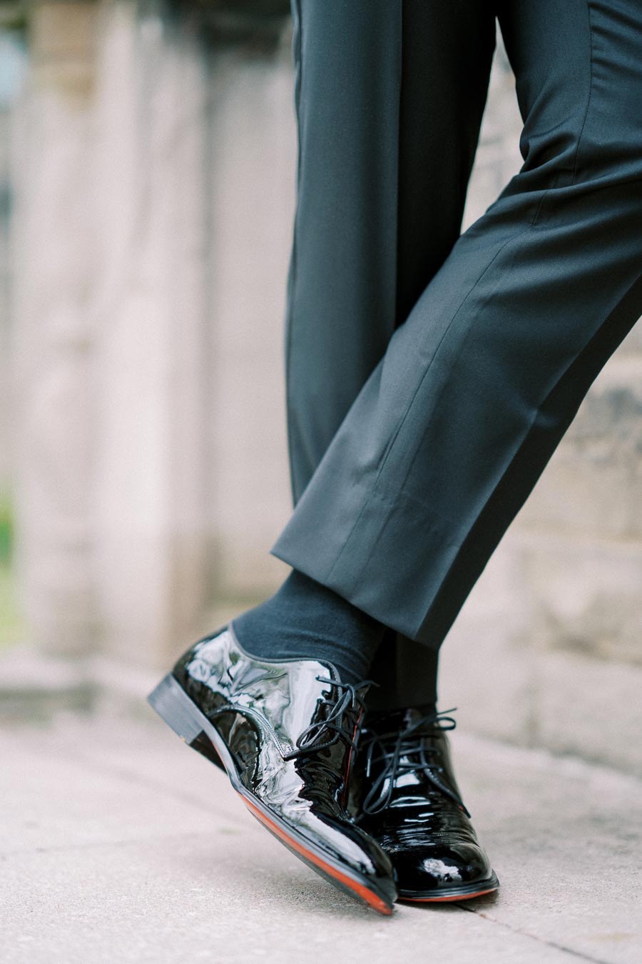 A pair of polished black dress shoes worn with dark socks and well-fitted black trousers, showcasing elegant men's formal fashion.