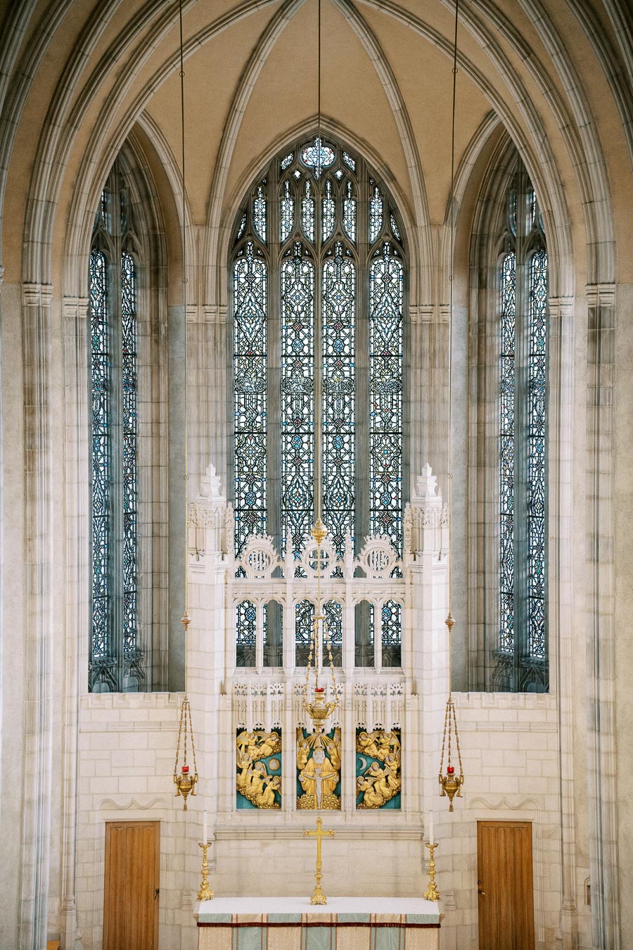 Intricate stained glass window and ornate altar inside a historic cathedral with vaulted arches and decorative details.