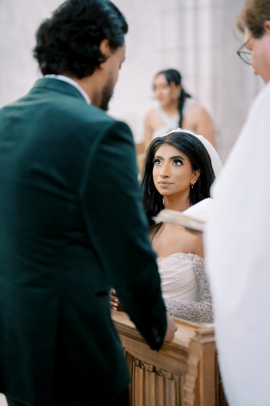 A bride and groom during their wedding ceremony at the altar, with the bride looking upward in a church setting.