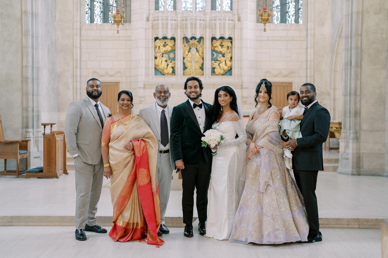 A diverse family posing for a wedding photo inside a grand church, with the bride and groom surrounded by family members in elegant attire.