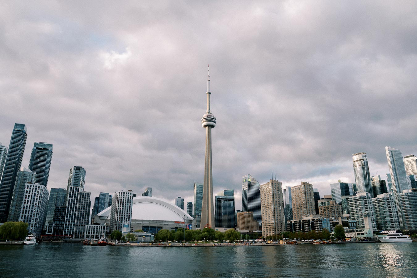 Toronto skyline with the prominent CN Tower on a cloudy day, viewed from the waterfront.