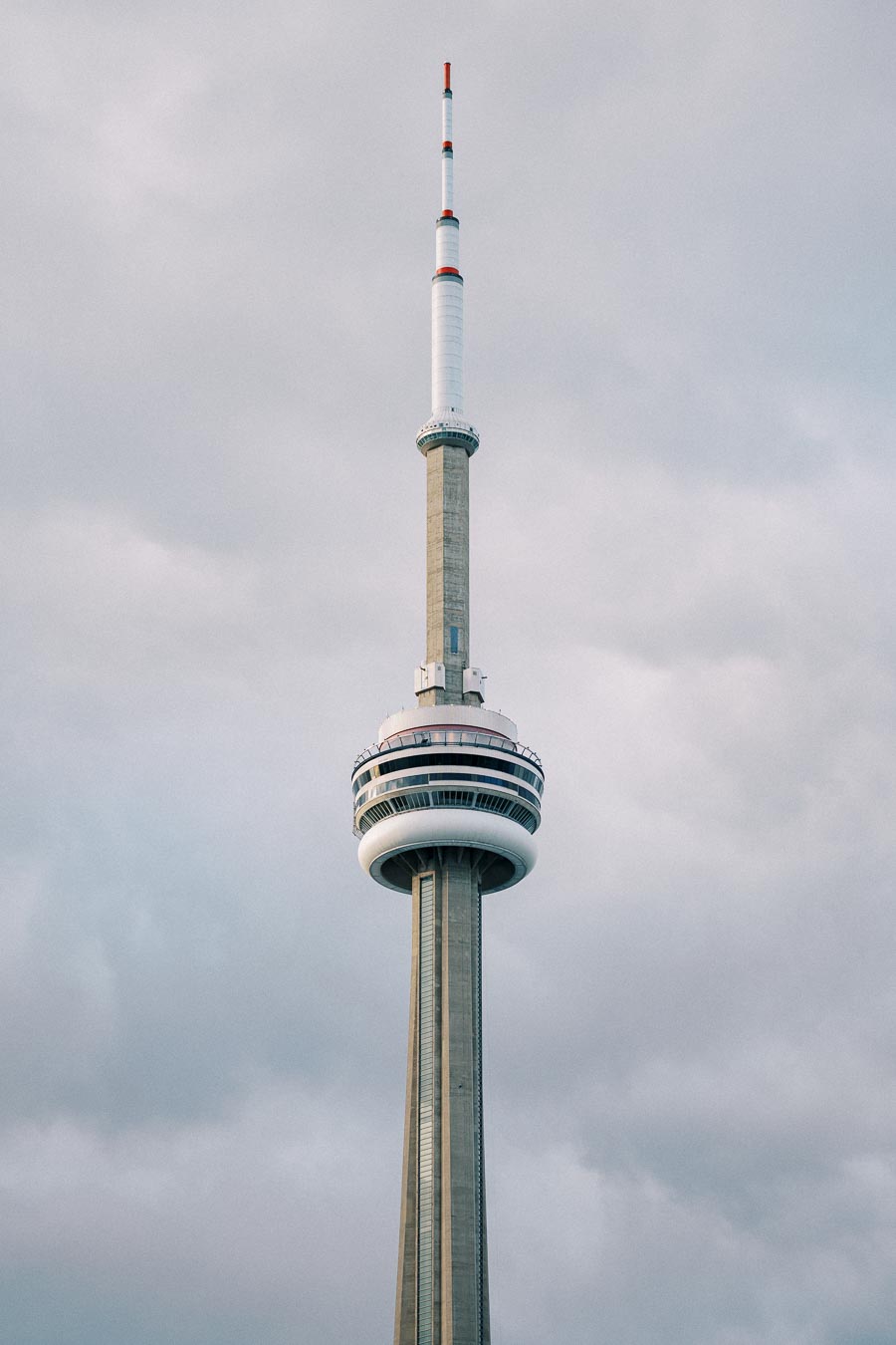 A tall telecommunications tower with an observation deck against a cloudy sky.