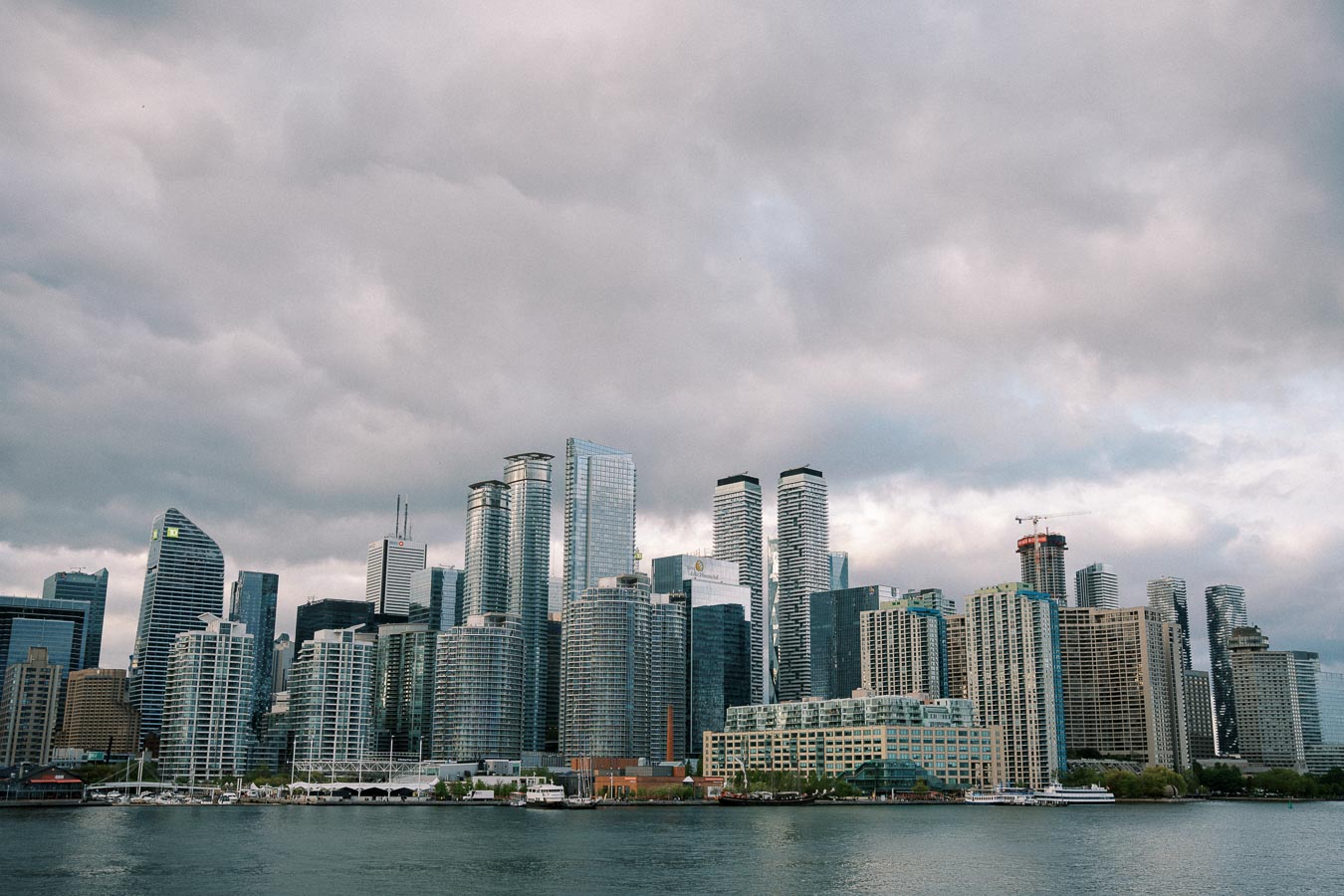 Skyline of modern skyscrapers overlooking a waterfront under a cloudy sky, highlighting urban architecture and city living.