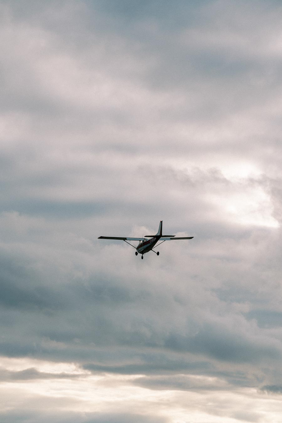 A small airplane flying through a cloudy sky.