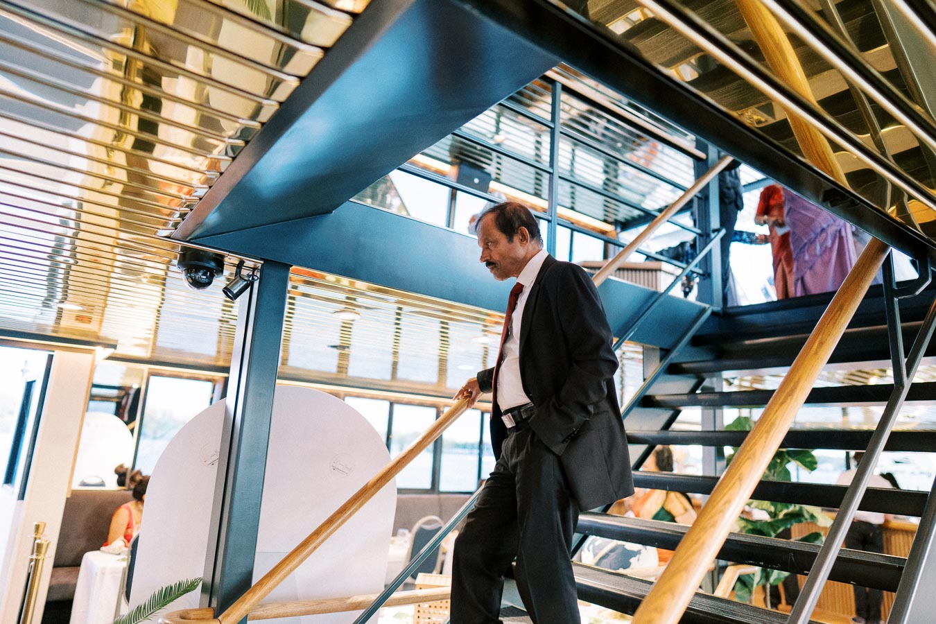Elegant man in a suit ascending modern staircase in sophisticated interior setting, emphasizing architectural design and business style.