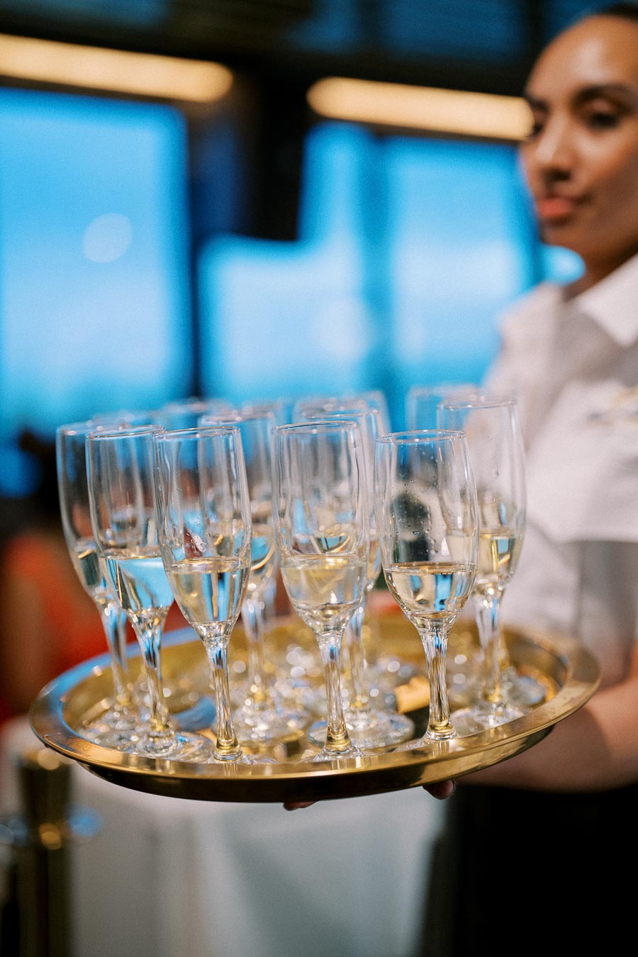 A waiter holding a tray filled with champagne flutes against a blurred background, ready for a sophisticated event or celebration.