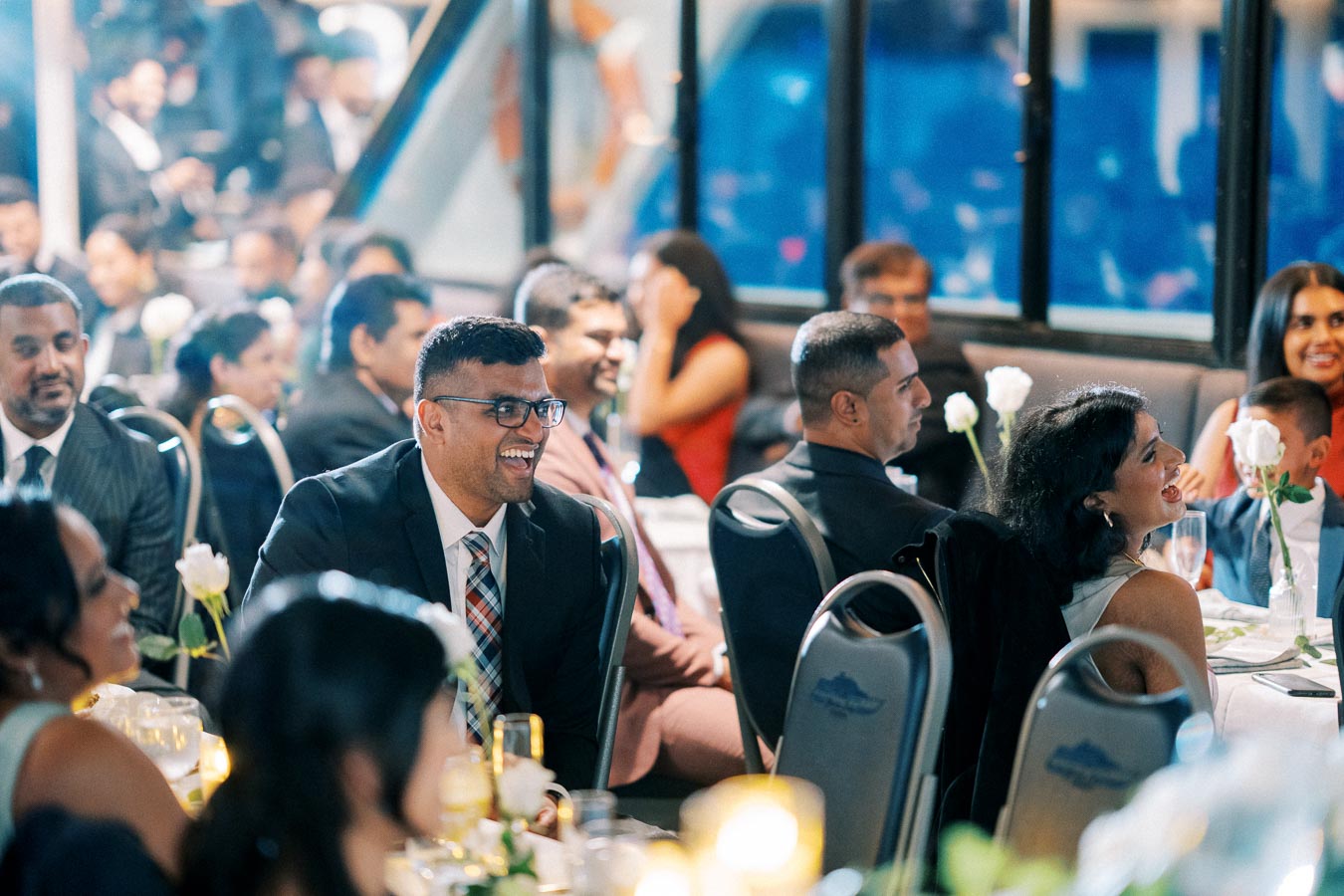 Guests enjoying a joyful moment at a formal event with elegant table settings and warm ambient lighting.