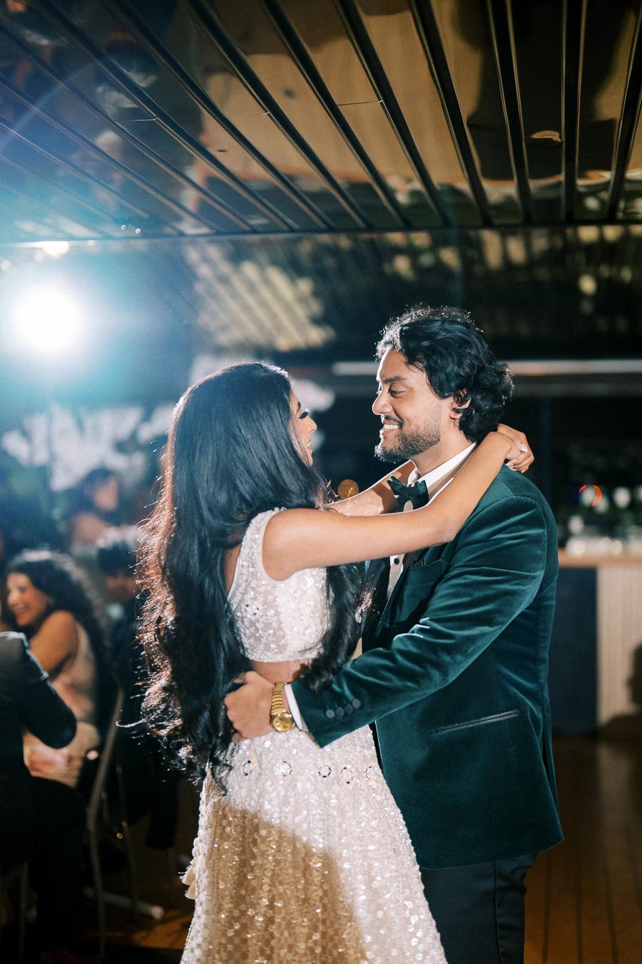 Elegant couple dancing at a wedding reception, woman in stunning gown and man in sharp suit, under romantic ballroom lighting.