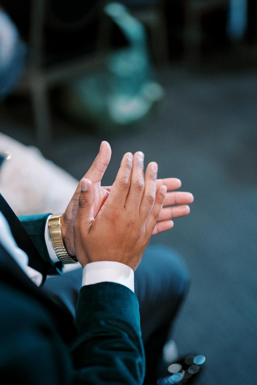 A person in formal attire clapping hands, highlighting a gold watch on the wrist, creating a celebratory and professional atmosphere.