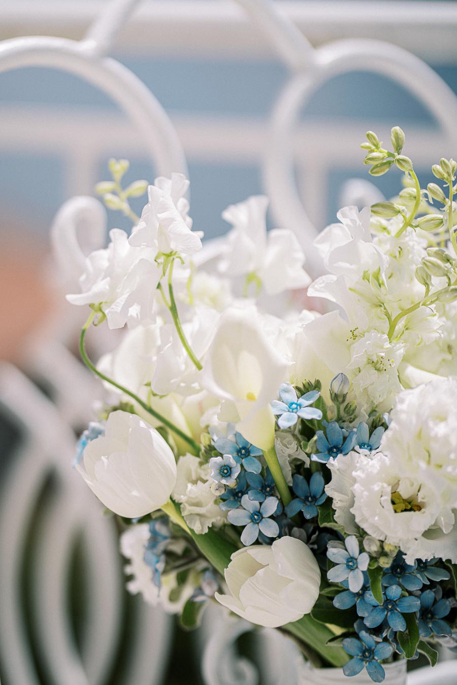 Bouquet of white tulips and delicate blue forget-me-nots against a soft background, creating a fresh and elegant floral arrangement.