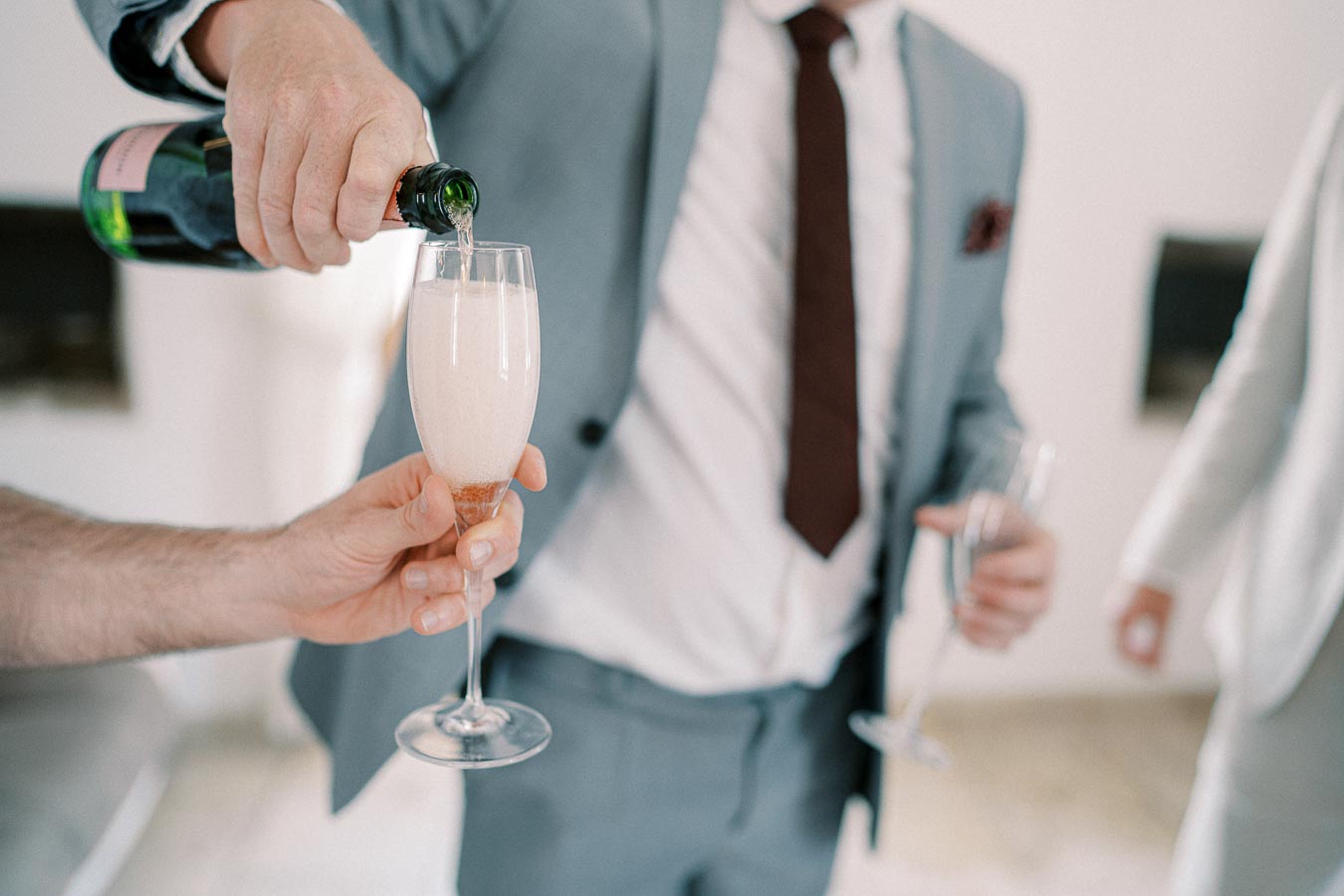 A person in a suit pouring champagne into a glass at a celebration or event.