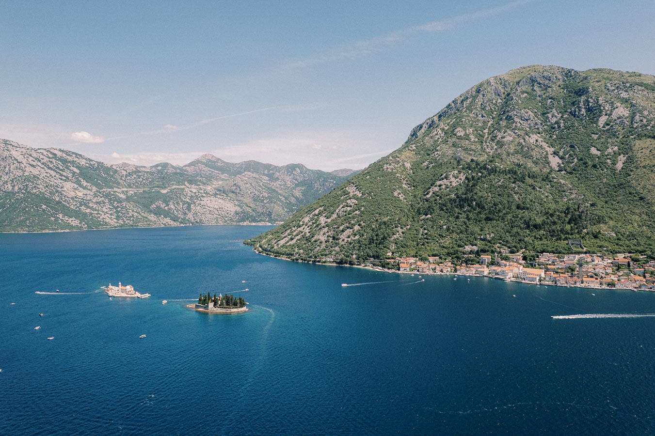 Aerial view of the Bay of Kotor in Montenegro, showcasing a deep blue sea, mountainous landscape, and two small islands. Perfect for nature tourism and travel promotions.