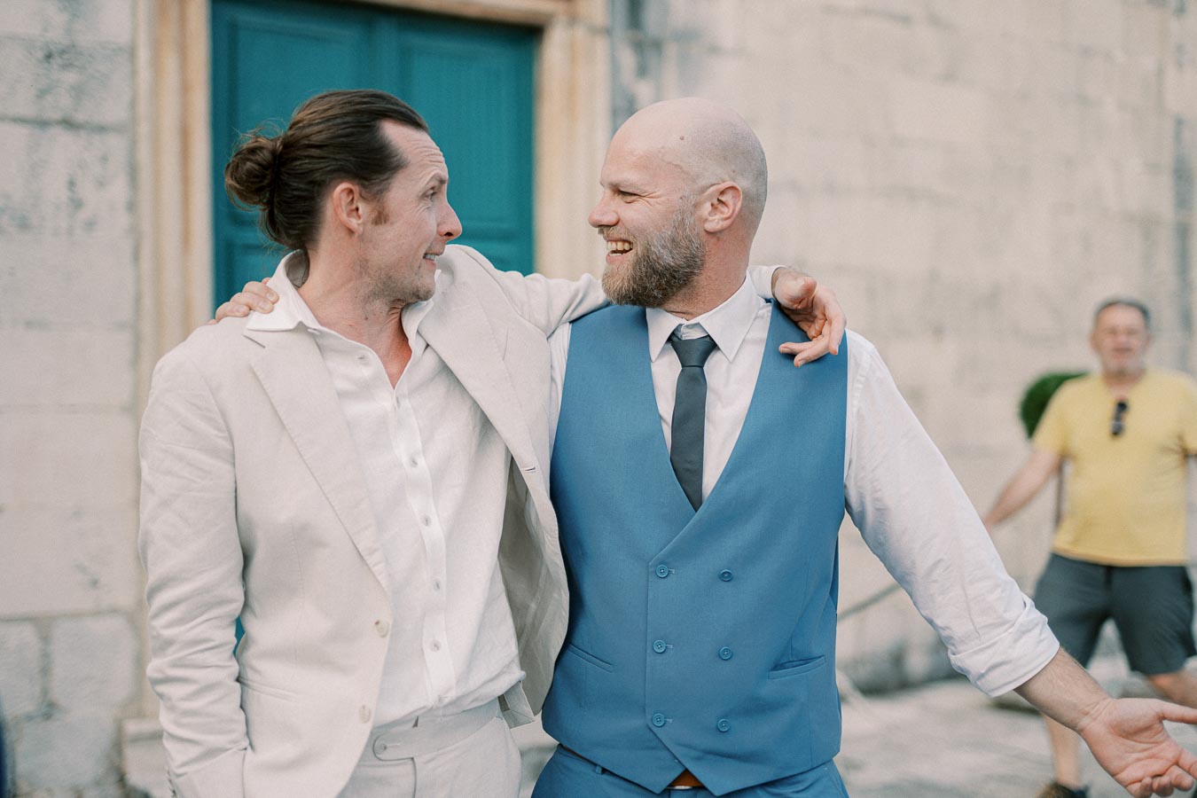 Two men in suits joyfully embracing outside a building.