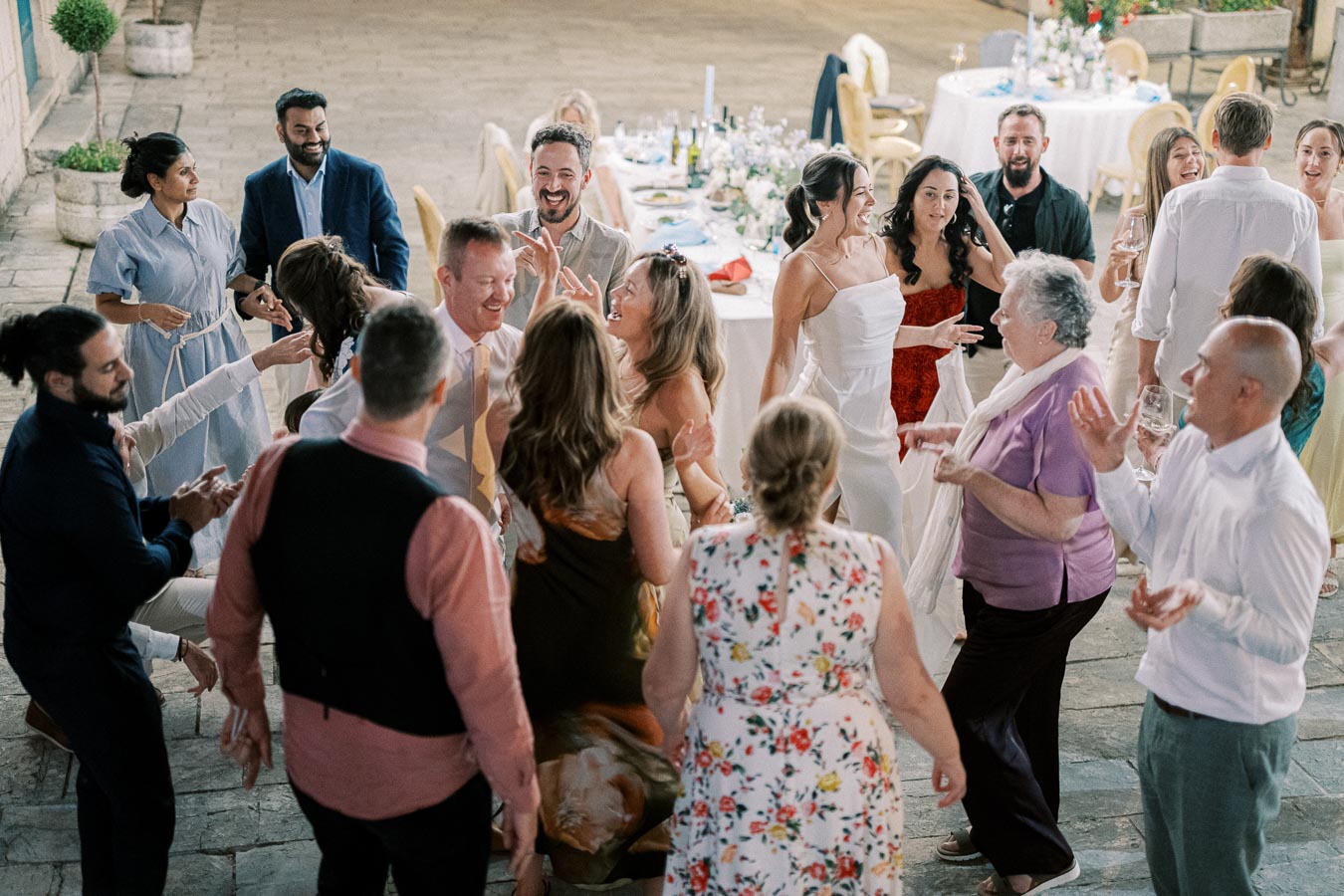 A lively wedding reception with guests dancing and celebrating, featuring a diverse group of friends and family enjoying the joyful atmosphere in an outdoor venue setting.