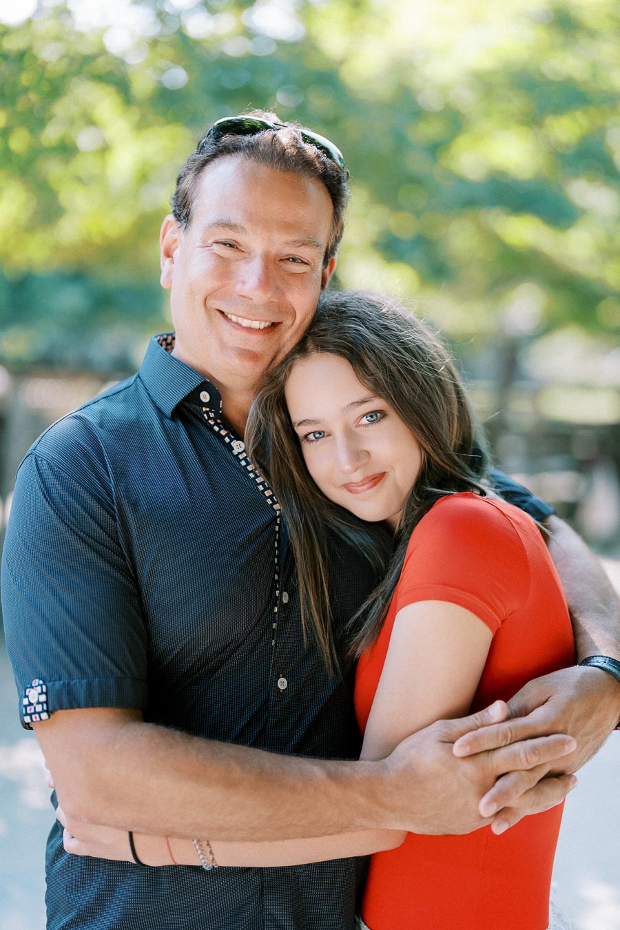 A cheerful couple embracing outdoors with a blurred green background, highlighting companionship and happiness.