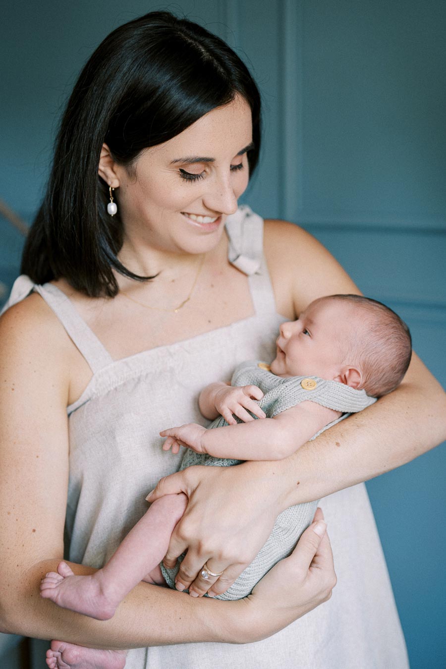 A mother lovingly holds her newborn baby in her arms, both gazing at each other.