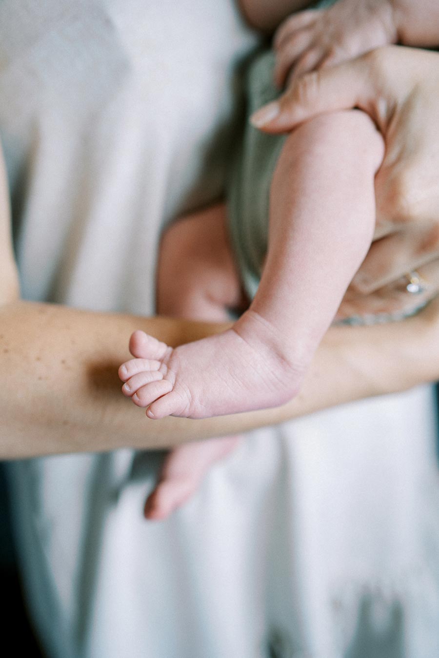 Close-up of a parent holding a newborn baby's legs, showcasing the delicate and tiny feet, symbolizing care and tenderness.
