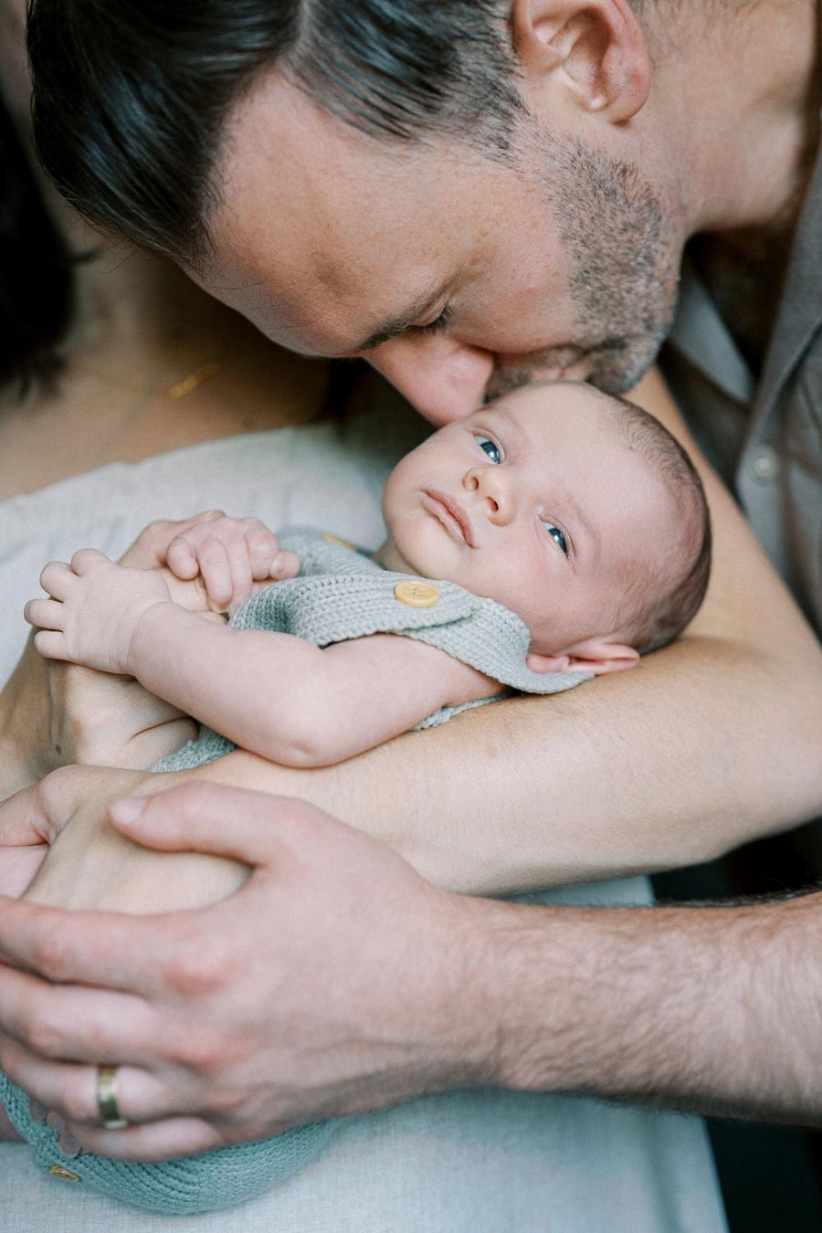 Father lovingly holding and kissing his newborn baby, capturing the tender bond and warmth of family moments.