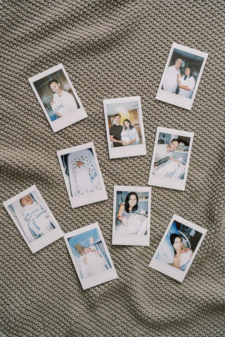 Polaroid photos of a newborn baby and family members arranged on a textured gray blanket, capturing precious family moments and new beginnings.