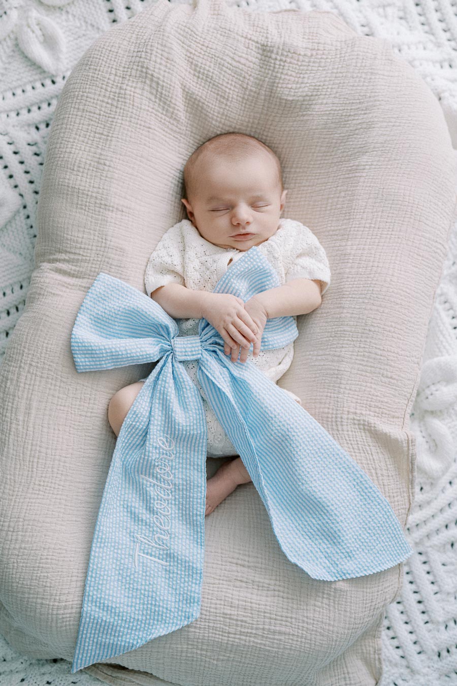 Newborn baby with personalized blue bow during in-home Toronto photoshoot by Toronto newborn photographer