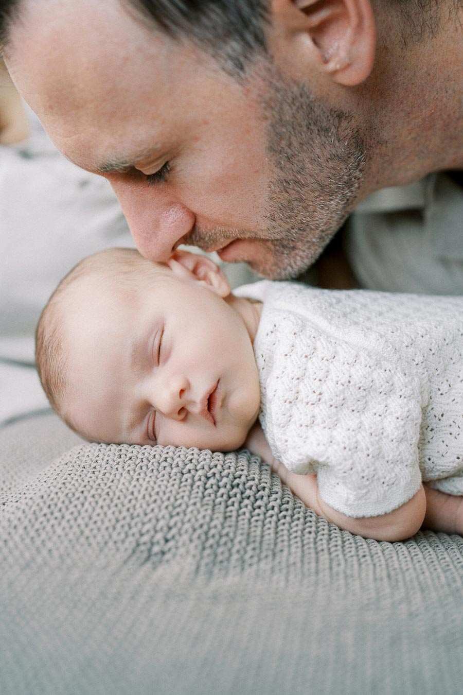 Father kissing newborn baby on the head during an intimate lifestyle session by Toronto newborn photographer