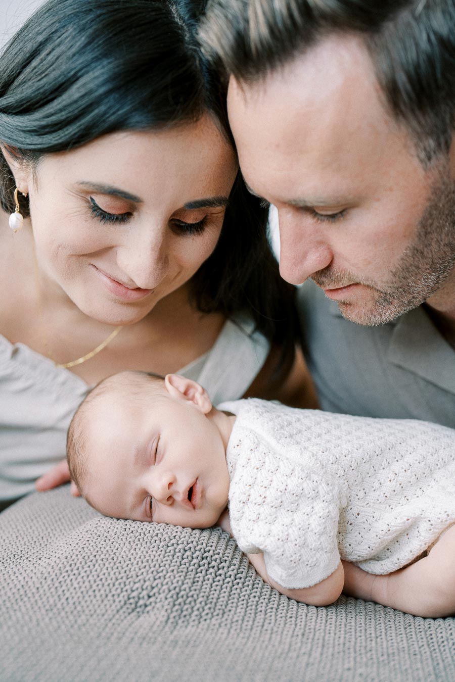 Sleeping newborn with loving parents during in-home lifestyle session by Toronto newborn photographer
