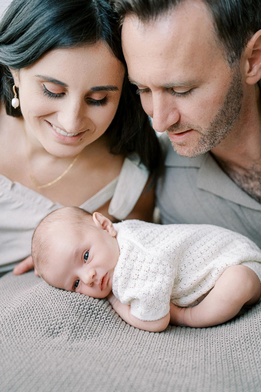 Parents holding their newborn baby at home during an in-home lifestyle session by Toronto newborn photographer