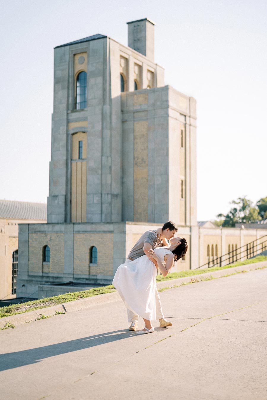 A couple sharing a romantic moment in front of a historic building, with soft sunlight creating a peaceful atmosphere.