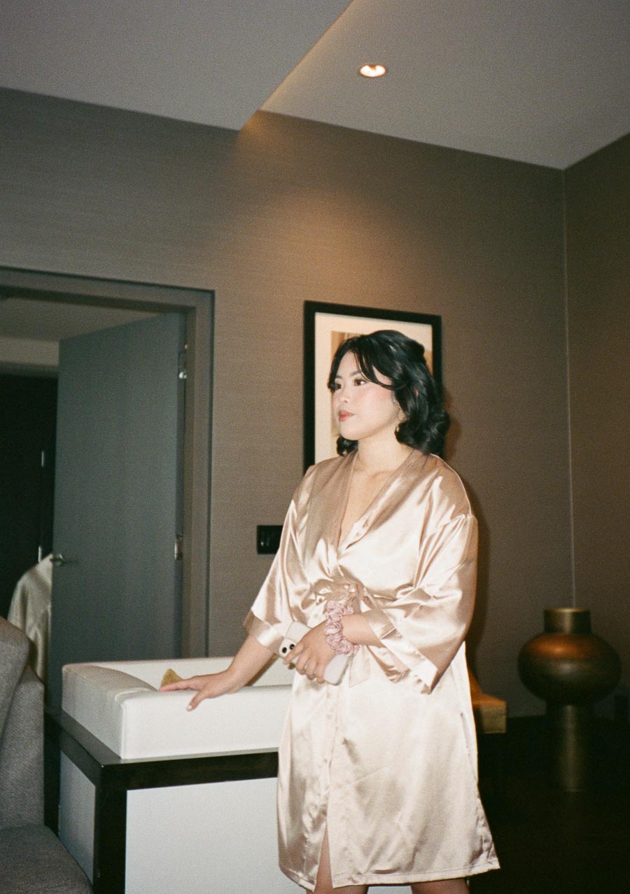 A woman in a satin robe stands in a modern, stylishly decorated room.