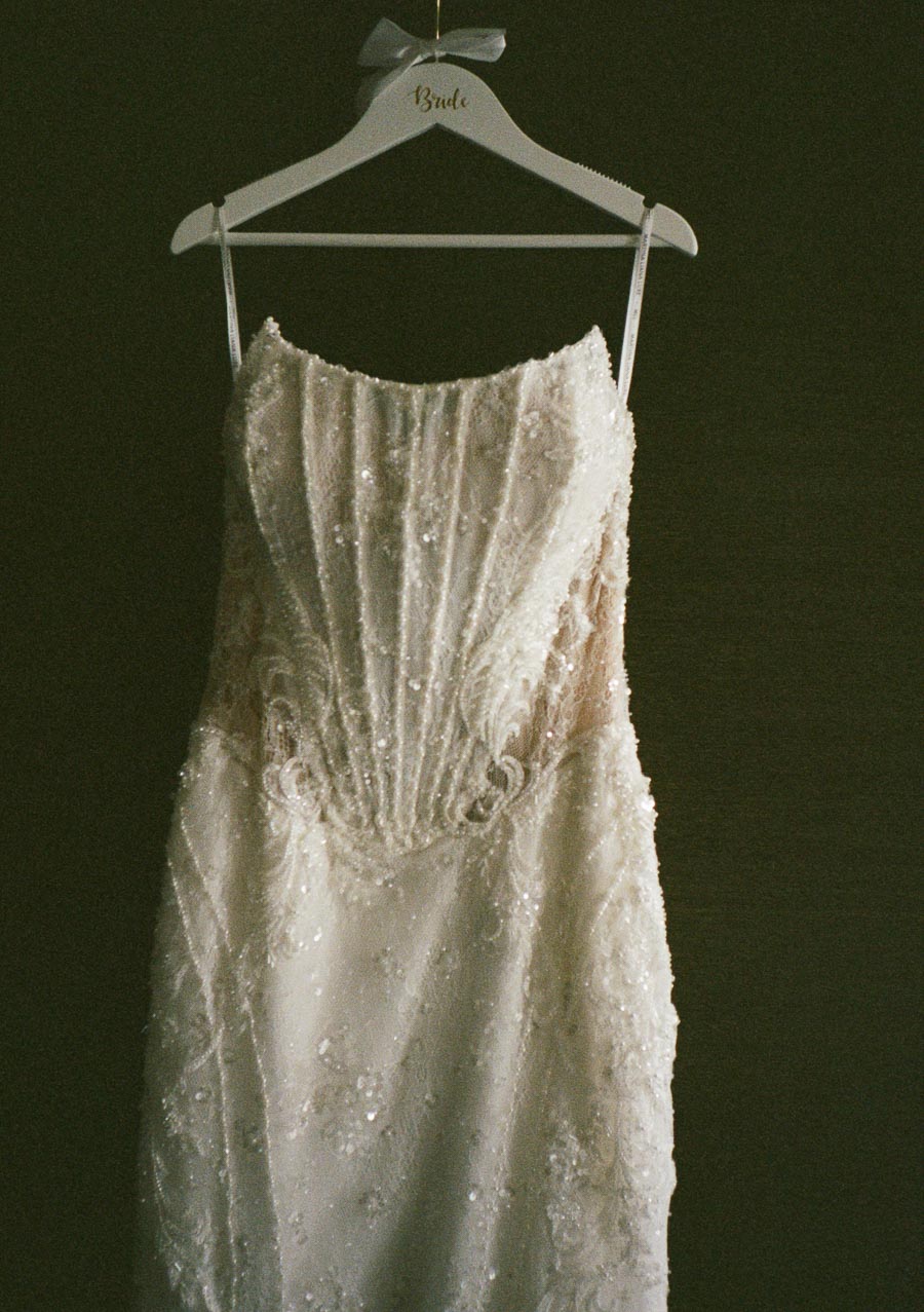 Elegant beaded wedding dress on a hanger, featuring intricate lace detailing and a fitted bodice, perfect for a glamorous bridal look.