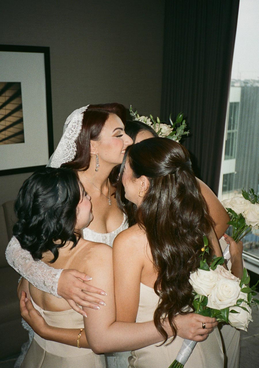 Bridesmaids warmly embracing the bride before the wedding ceremony, celebrating friendship and love.