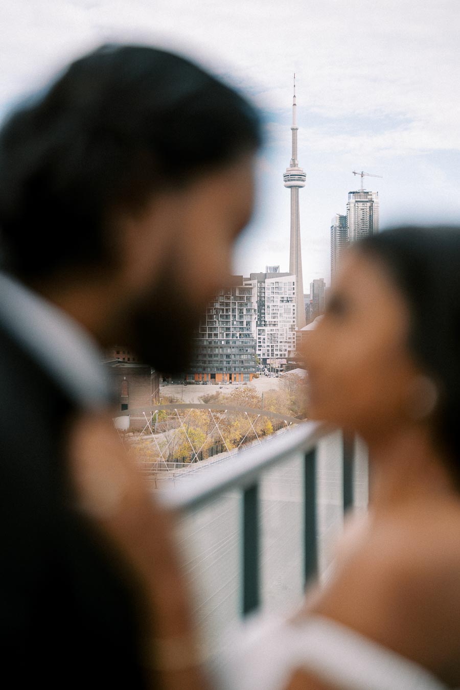 Blurry romantic couple with Toronto's CN Tower in the background on an overcast day.