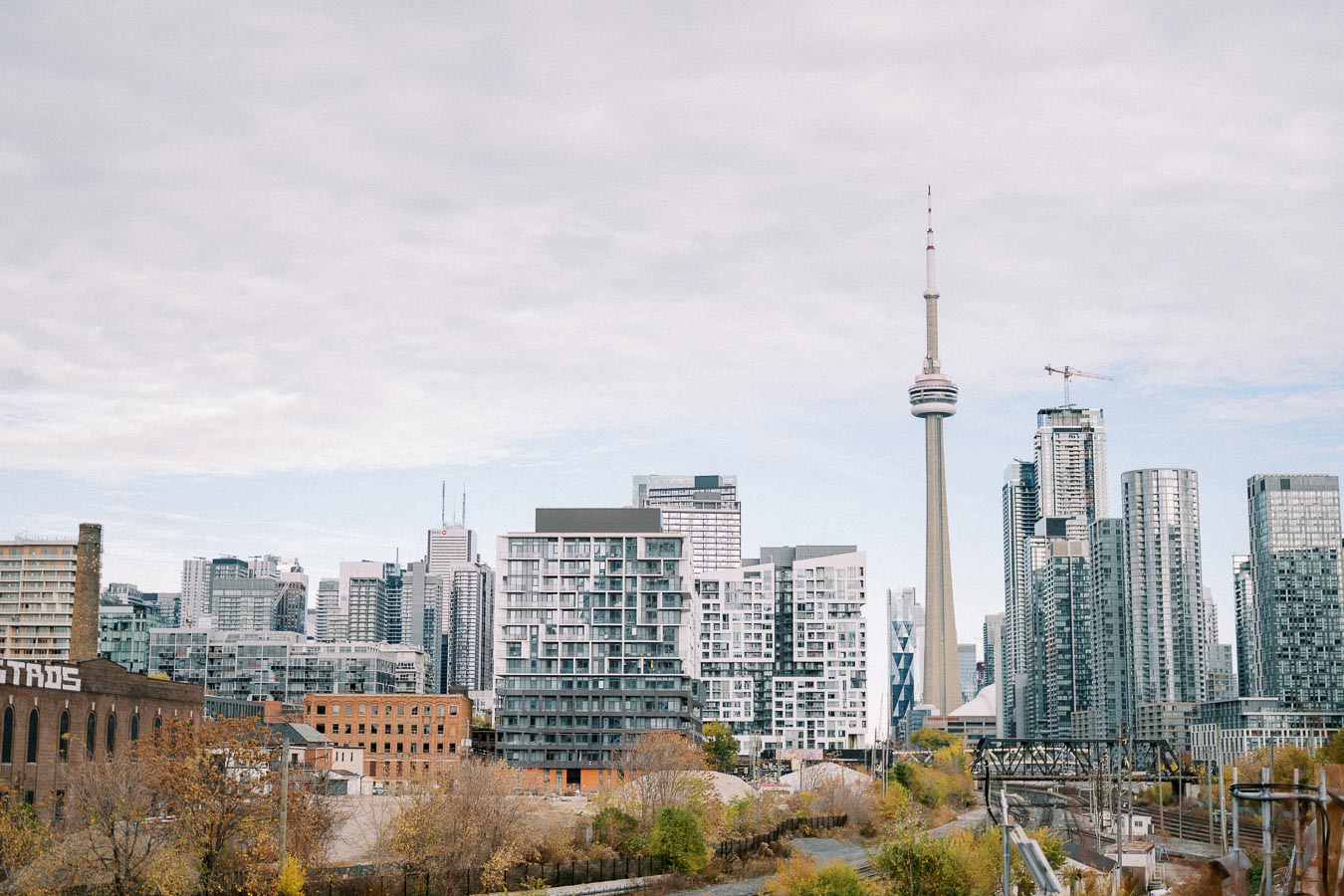 Toronto skyline with CN Tower and modern skyscrapers under a cloudy sky.